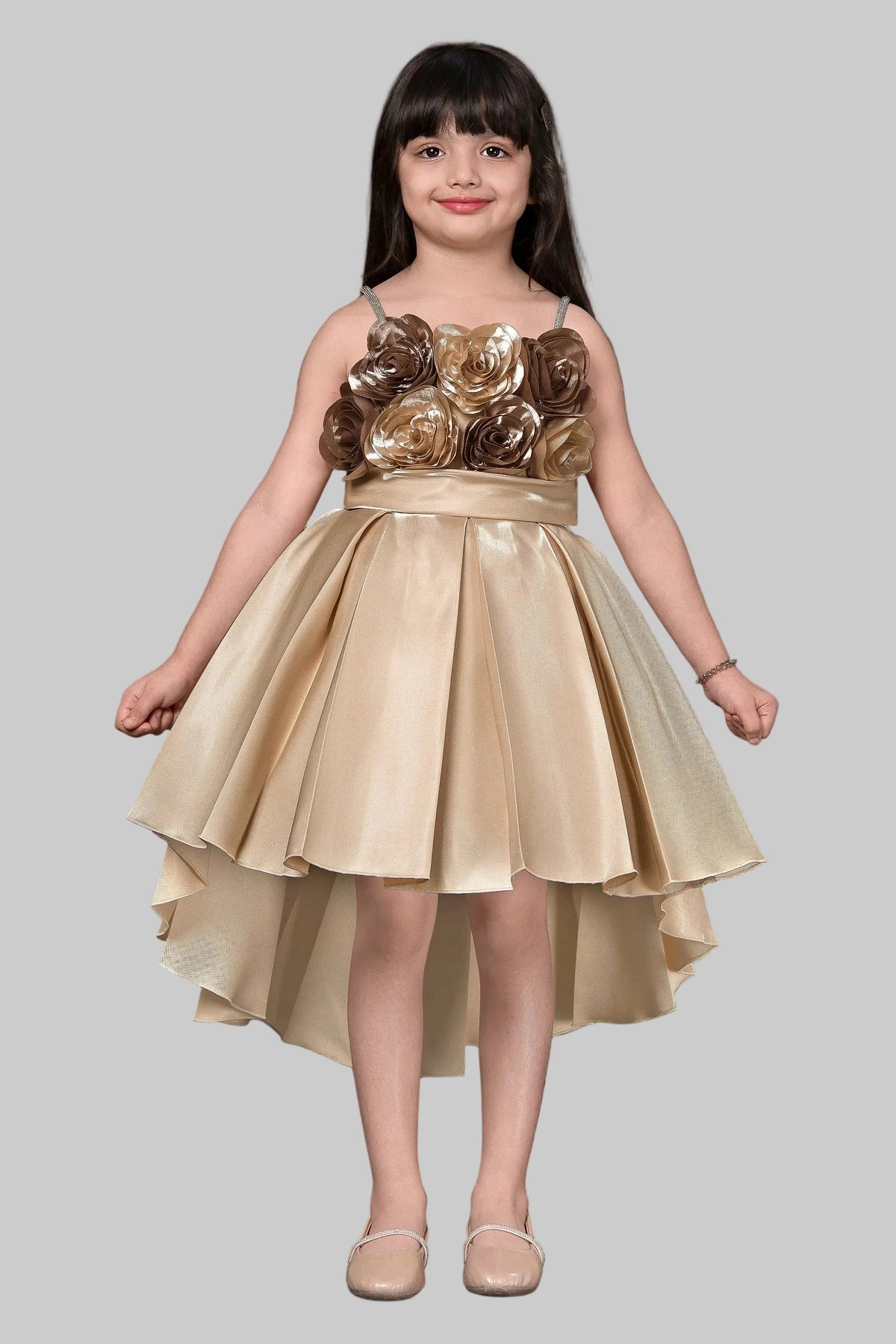 Young girl wearing a gold dress with floral embellishments against a dark background